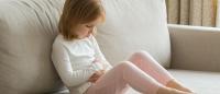 little girl on couch with a stomach ache